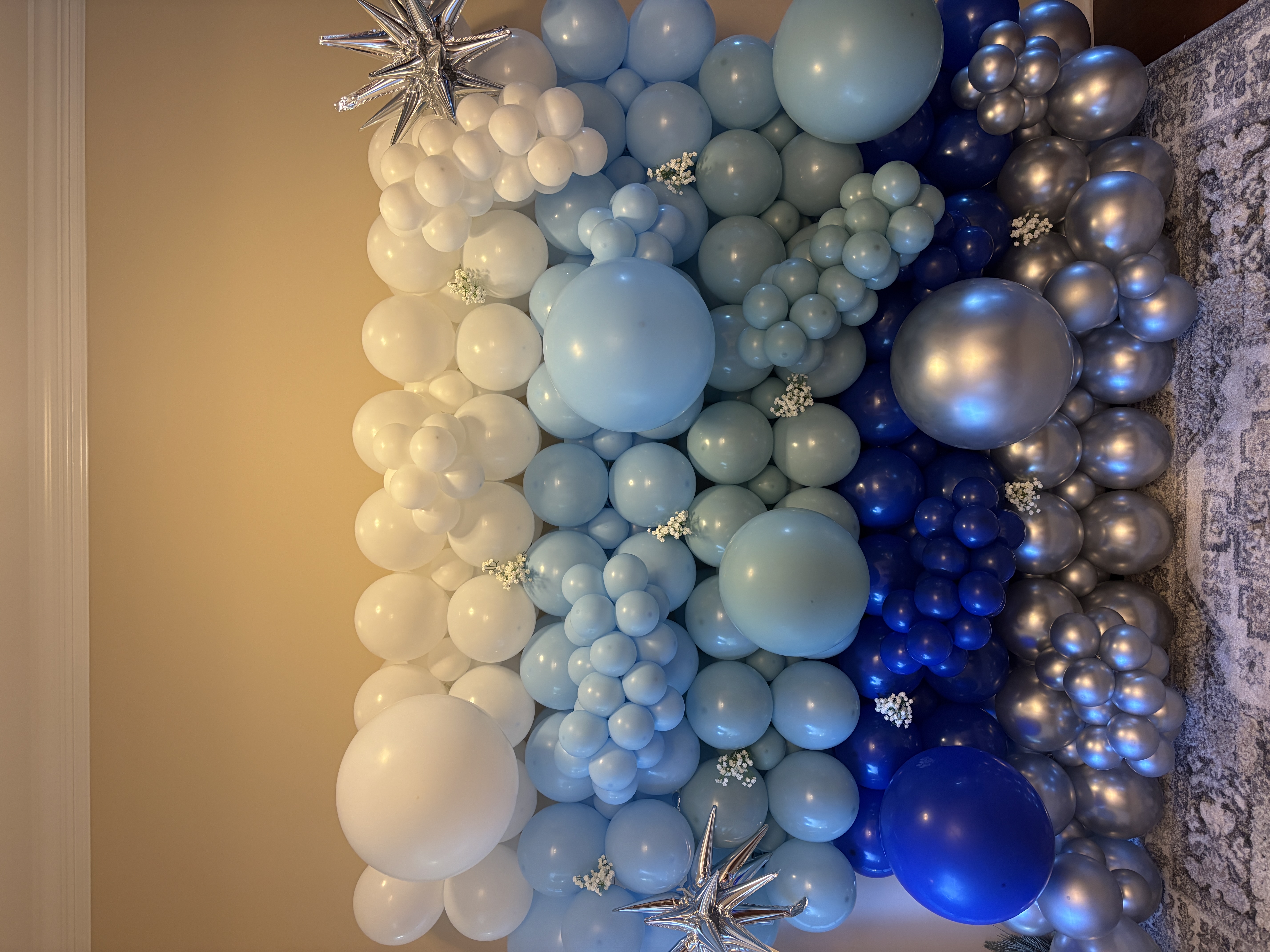 Blue, white, and silver balloon wall with floral and star accents
