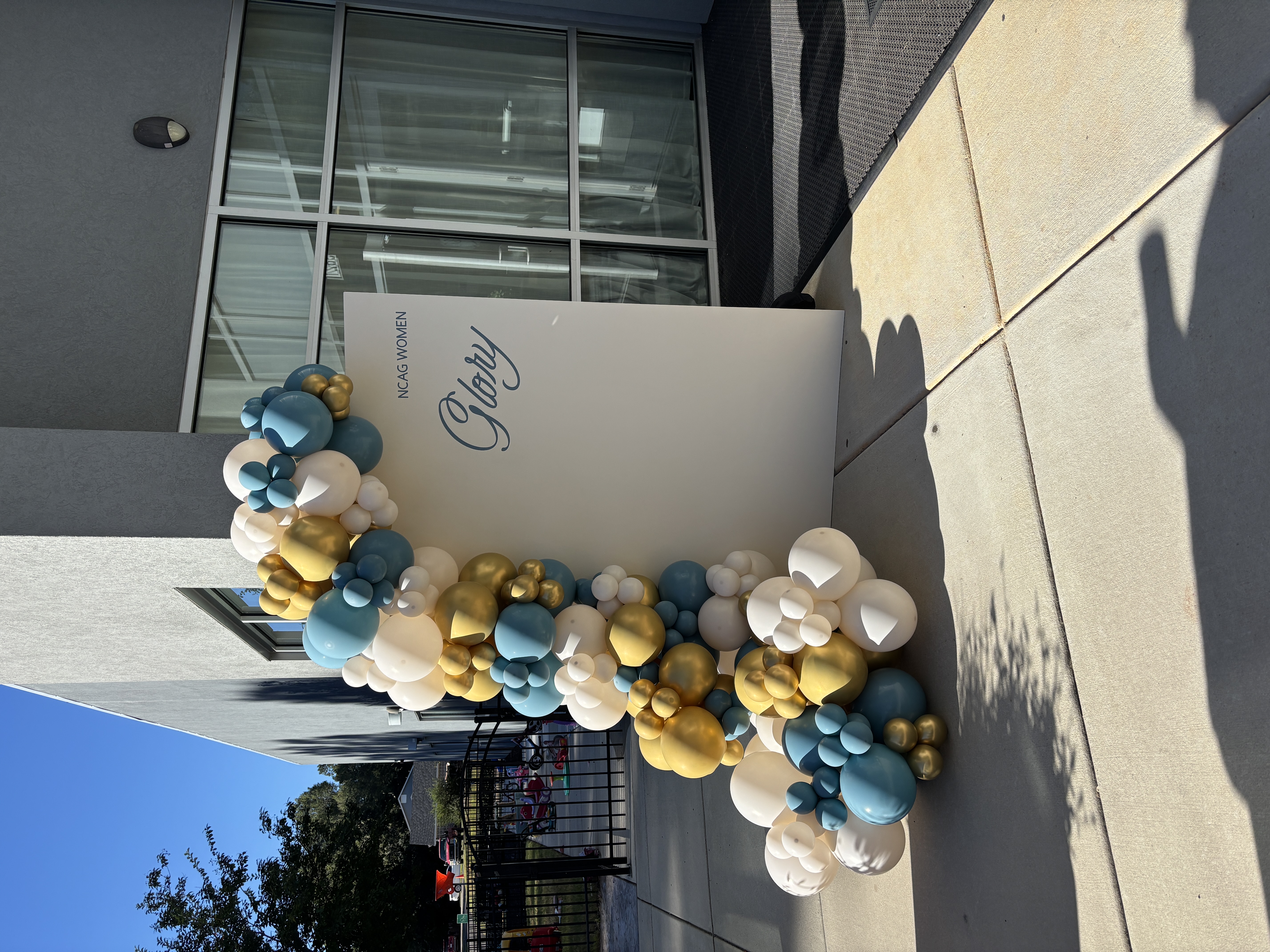 Teal, ivory, and gold balloon garland beside a Glory event backdrop