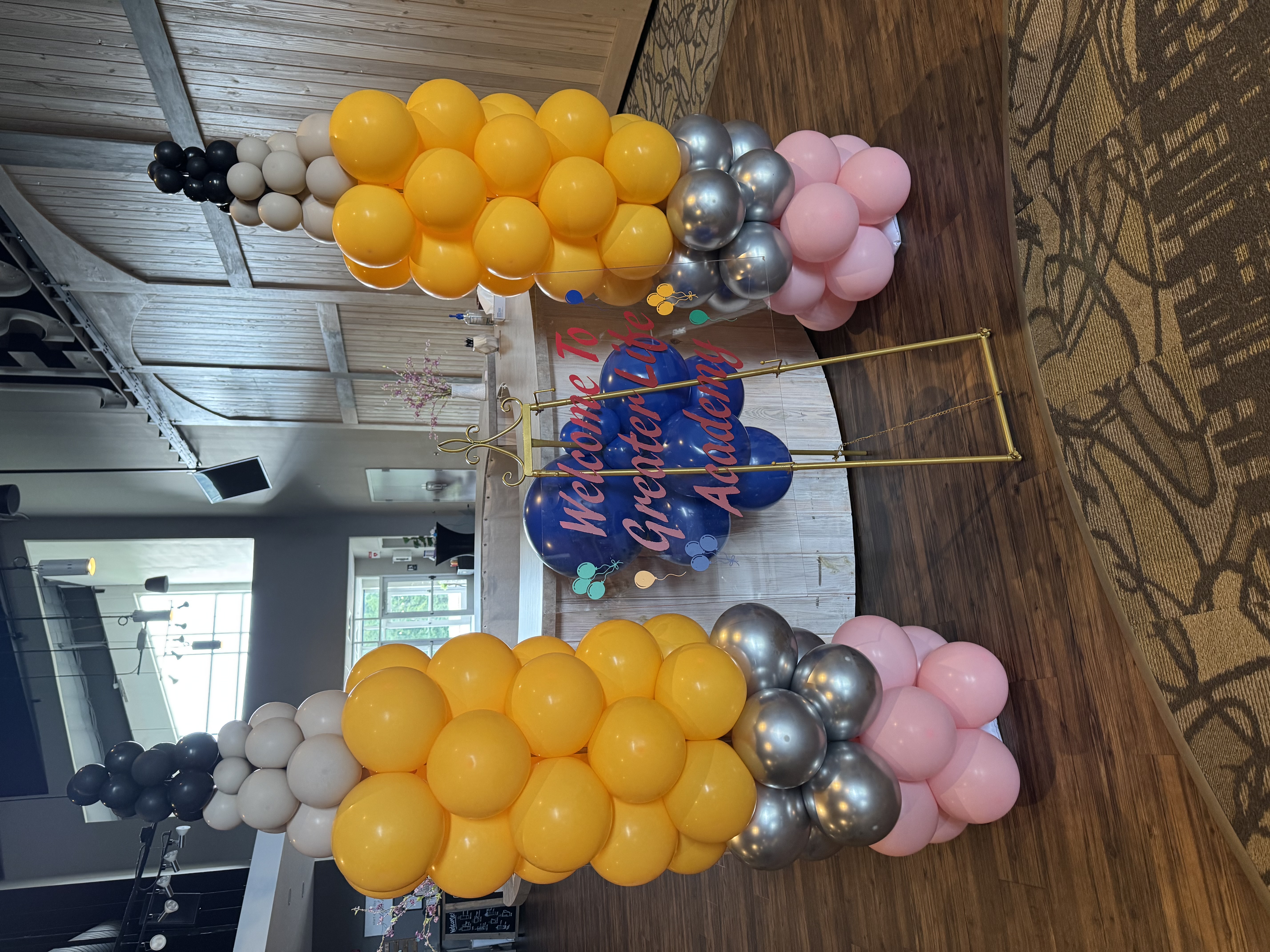 Pencil-shaped balloon columns framing a Greater Life Academy welcome sign
