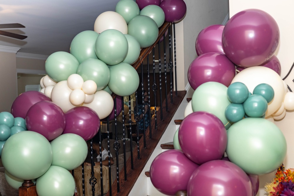 Close-up of plum, sage, and cream balloon garland on a staircase