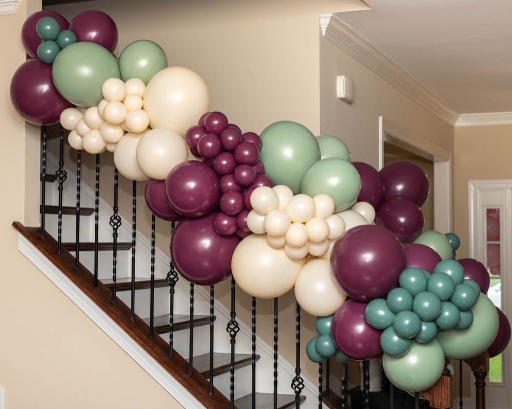Plum, sage, and cream balloon garland along a staircase