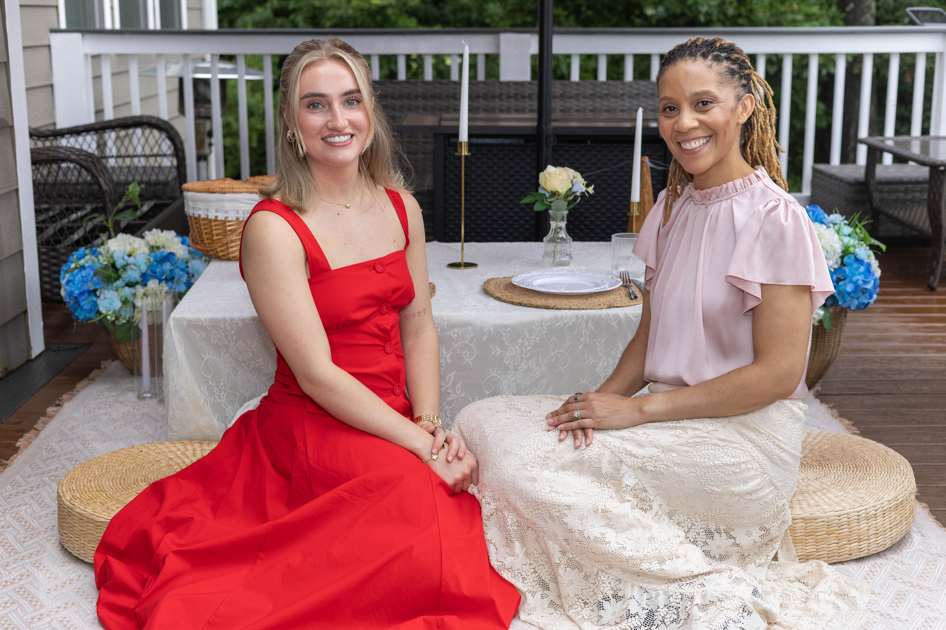 Two women seated beside a styled table with blue and white florals